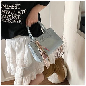Gros plan du sac cabas bleu clair en cuir avec fermoir argenté et bijou de sac boho