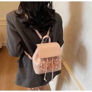 Close-up of pink mini backpack with pearl accents and mesh drawstring on model