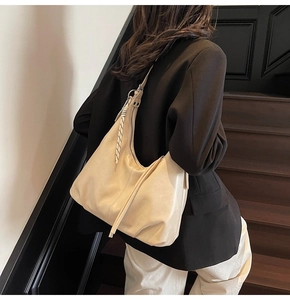 Detail of beige hobo bag with pebble leather texture and decorative striped scarf