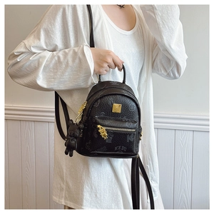 Detailed view of black mini backpack with golden zipper and KEBU bear pendant