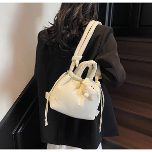 Detail of cream quilted bucket bag with side drawstring and plush sheep pendant