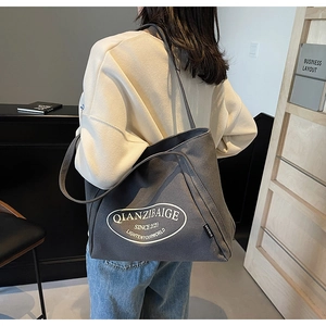 Detalle del bolso tote de lona gris que muestra la textura y el logotipo impreso