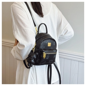 Close-up of black teddy print leather backpack with golden hardware and bear charm