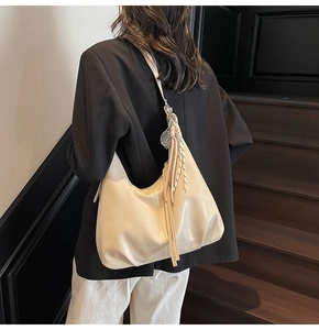 Detail of beige hobo bag with fringe tassel and tennis racket charm on leather strap