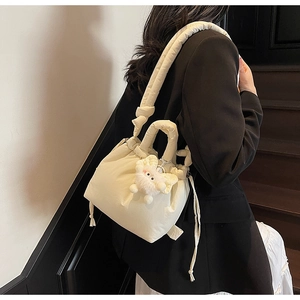 Detail of cream quilted puffer bucket bag with knotted strap and plush sheep charm