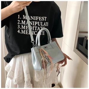 Détail d'un sac à main bleu clair avec fermoir rotatif argenté et charm d'ours