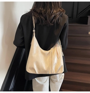 Close-up of a beige hobo bag with tassel details worn by a model on a modern staircase