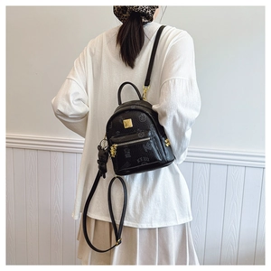 Mini black backpack with gold hardware and plush bear charm shown on model