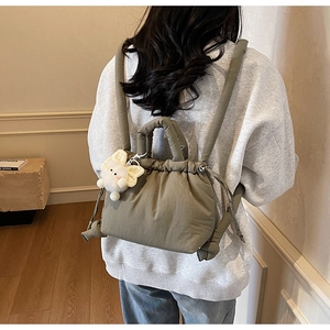 Detail of olive green quilted backpack featuring plush bunny charm and drawstring closure