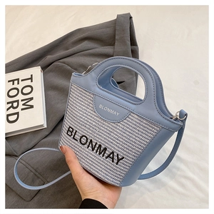 Detalle del bolso de cubo tejido en azul y blanco con asas redondas y correa