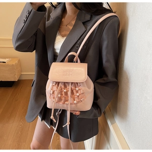 Detail of pink mini backpack with mesh pocket and pearl accents on elegant model