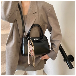 Détail du sac cabas en cuir noir avec fermoir rotatif argenté et porte-clé petit ours