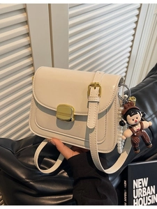 Off-white minimalist PU leather crossbody bag with gold buckle and pearl doll charm