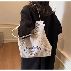 Primer plano de un bolso tote de lona beige grande con logo azul y correas