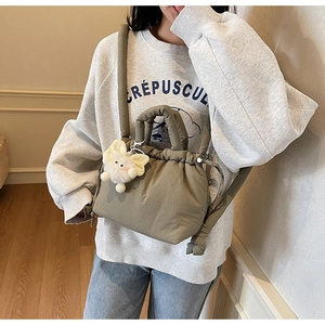 Quilted sage green bucket bag detail with drawstring closure and plush cat charm