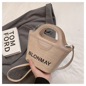 Detalle del bolso de paja BLONMAY con ribete de cuero crema y bordado en el frente
