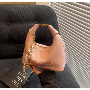 Close-up of pink crescent handbag with gold hardware and logo embossing details