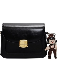Minimalist black glossy small crossbody bag with golden buckle and a cute doll charm