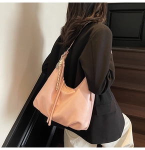 Detail of light pink hobo bag with woven strap and long tassel fringe accessories