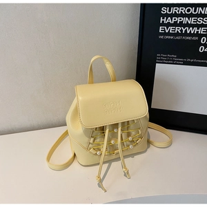 Detail of mini cream yellow backpack featuring embossed logo and elegant pearl accents