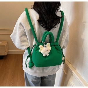 Green drawstring backpack with plush butterfly charm shown on model back view