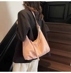 Peach pink hobo bag with braided handle and long tassel detail shown on model