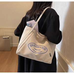 Primer plano de bolso tote de lona crema con gran capacidad y detalle de logo