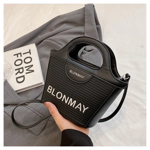 Detalle del bolso de cubo negro en cuero y tejido con asa sobre un fondo elegante