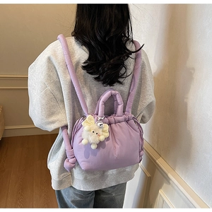 Detail of light purple quilted backpack with thick straps and white plush rabbit charm