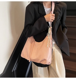 Detail of pink hobo shoulder bag featuring woven rope and leather tassel decoration