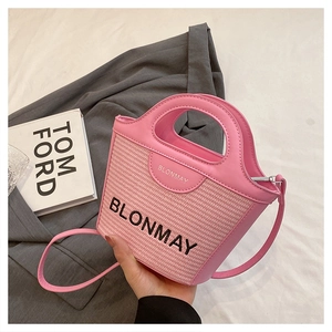 Detalle de bolso de paja rosa con asas de cuero y logotipo de BLONMAY bordado