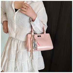 Détail du sac fourre-tout rose en similicuir avec fermoir rotatif argenté et breloques