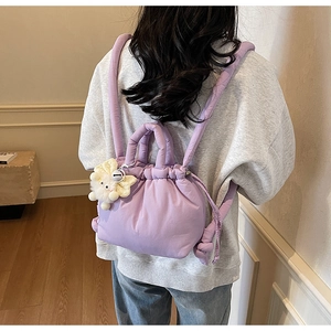Detail of light purple puffy drawstring bucket bag with cute white plush dog charm