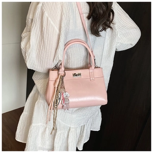 Détail du sac à main rose avec cuir texturé, fermoir rotatif et breloque ourson