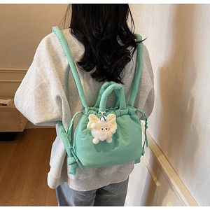 Detail of mint green padded bucket bag with soft drawstring and cute plush pendant