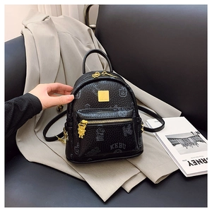 Close-up of mini black PU leather backpack with bear charm and golden metallic hardware