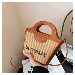 Detalle del bolso tipo cubo de paja con ribete de cuero marrón y marca BLONMAY