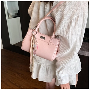 Détail du sac à main rose avec fermoir rotatif argenté et breloque chien mignonne