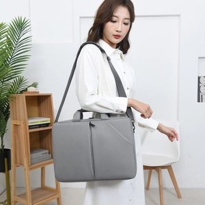 Modèle asiatique portant une mallette grise minimaliste pour ordinateur portable