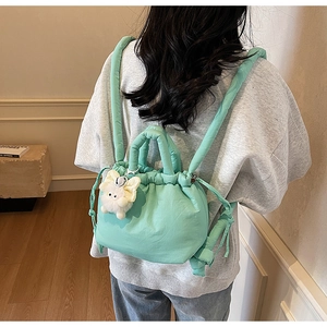 Detail of mint green quilted backpack with drawstring closure and plush pendant charm