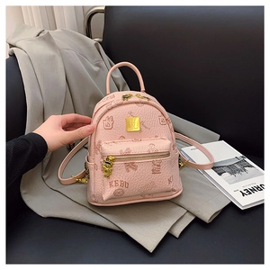 Macro view of pink pebbled leather mini backpack with bear prints and golden charm
