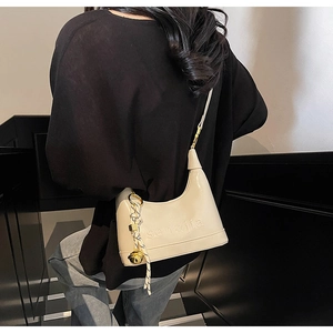 Detail of beige underarm bag with sen&jia embossed text and gold bell charm