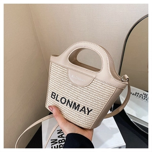 Detalle del bolso tipo cubo de paja BLONMAY con ribetes de cuero y bordado frontal
