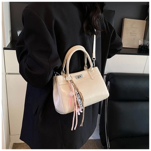Détail du sac fourre-tout crème avec poignées, fermoir rotatif en métal et pompon