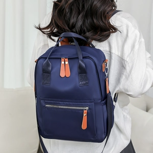 Sac à dos en tissu oxford bleu foncé avec garniture en cuir porté par un modèle