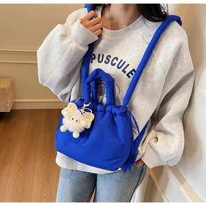 Detail of blue quilted puffer bucket bag with cute plush sunflower charm on a model