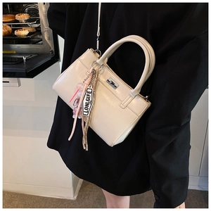 Détail du sac à main blanc cassé avec fermoir rotatif argenté et breloques de mode