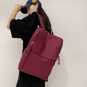 Vue détaillée d'un sac à dos d'ordinateur bordeaux en nylon avec rabat et poches zippées