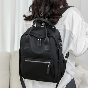 Détail d'un sac à dos en nylon noir minimaliste avec doubles poignées et détails argentés