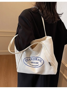 Bolso tote grande de lona blanca con estampado gráfico azul llevado por una modelo